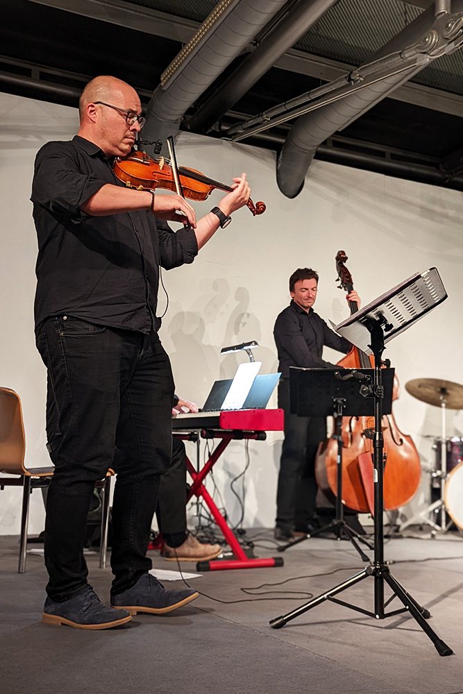 Musikschullehrer Michael Leitner spielt im Vordergrund Flöte, Musikschullehrer Ewald Prügger am Bass im Hintergrund